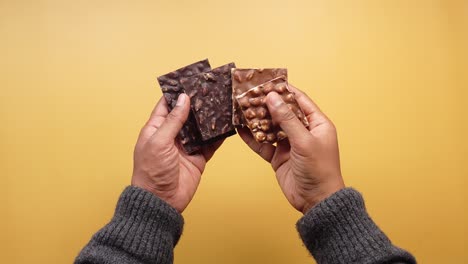 close up shot of a person holding a chocolate bar with hazelnuts