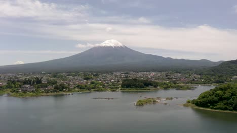 Aerial-of-iconic-and-majestic-volcano-Mount-Fuji-with-scenic-landscape,-lake-Kawaguchi,-and-snow-capped-peak-on-clear-day-in-Fuji,-Japan
