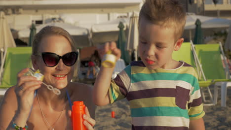 mother and son blowing soap bubbles on the beach