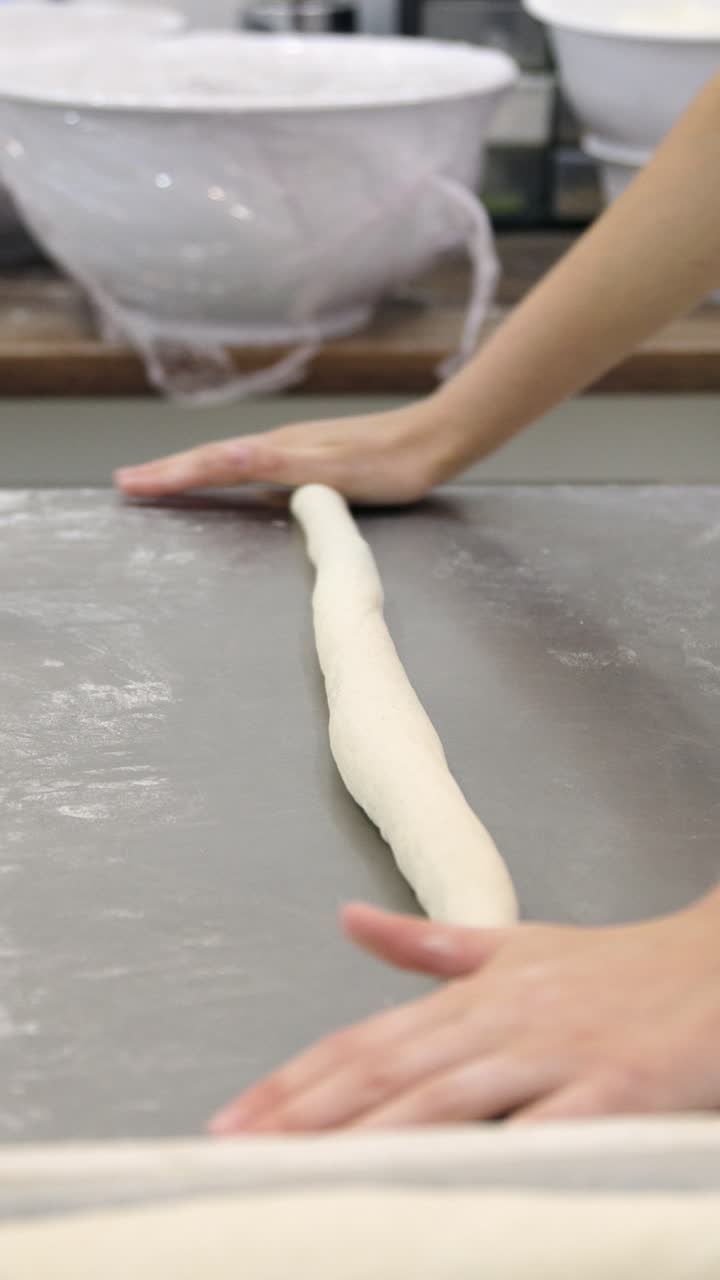 Hands Rolling and Shaping Dough on a Metal Counter