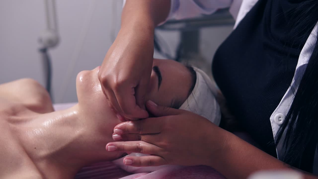 Professional face care in spa salon. Young woman is receiving face massage made by professional cosmetologist. Beauty, healthy