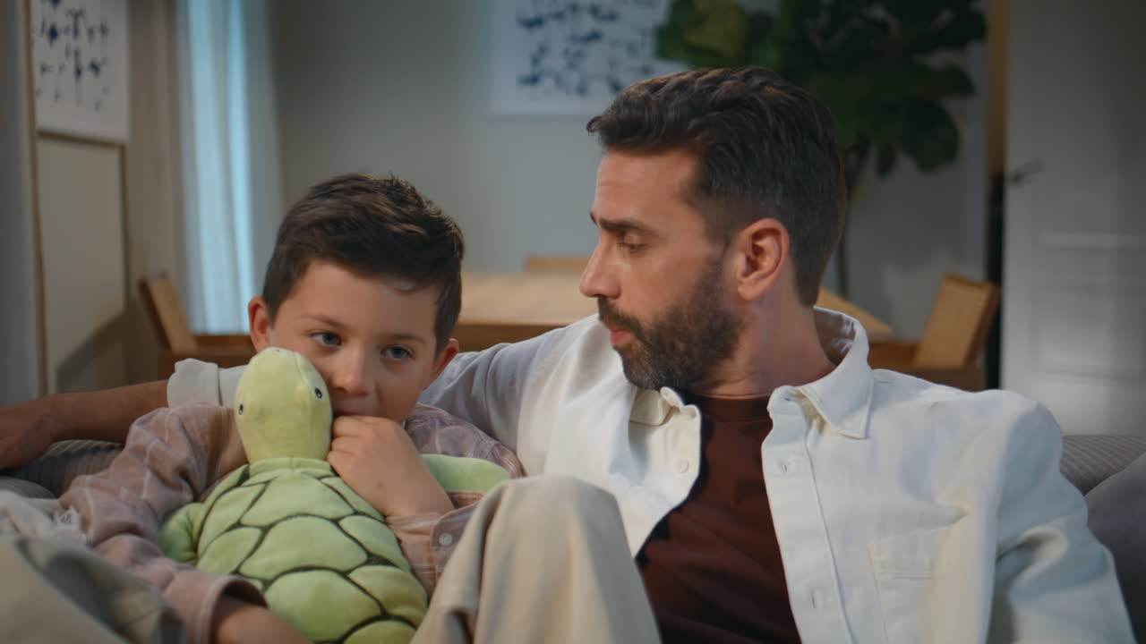 Primo piano di padre single che crea un legame con il figlio in un accogliente appartamento serale. Uomo che coccola il bambino
