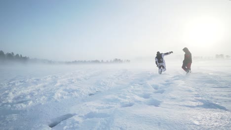 a wide shot of two people walking on a frozen lake in the storm