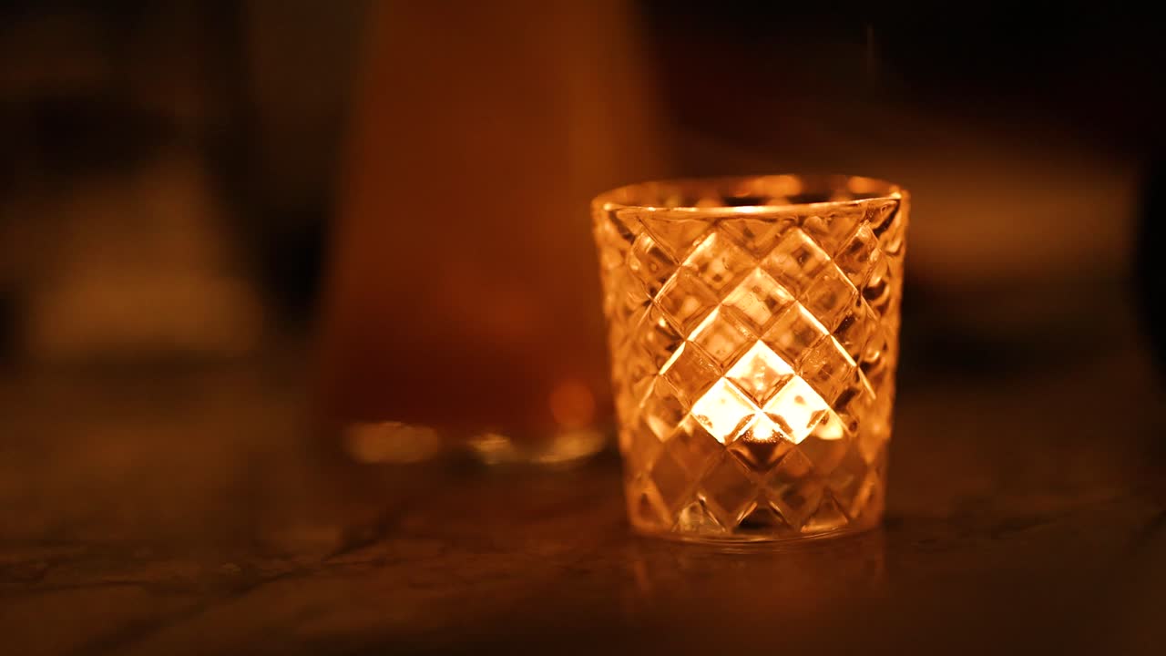 A flickering candle in a glass holder creates a warm, intimate atmosphere. Soft lighting enhances the cozy, tranquil mood