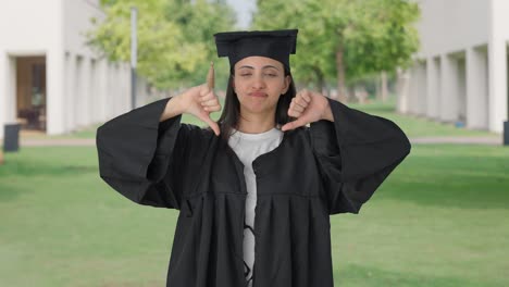 chica graduada de la universidad india decepcionada mostrando pulgares hacia abajo señal