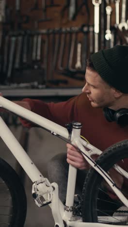 man repairing a white mountain bike in a workshop