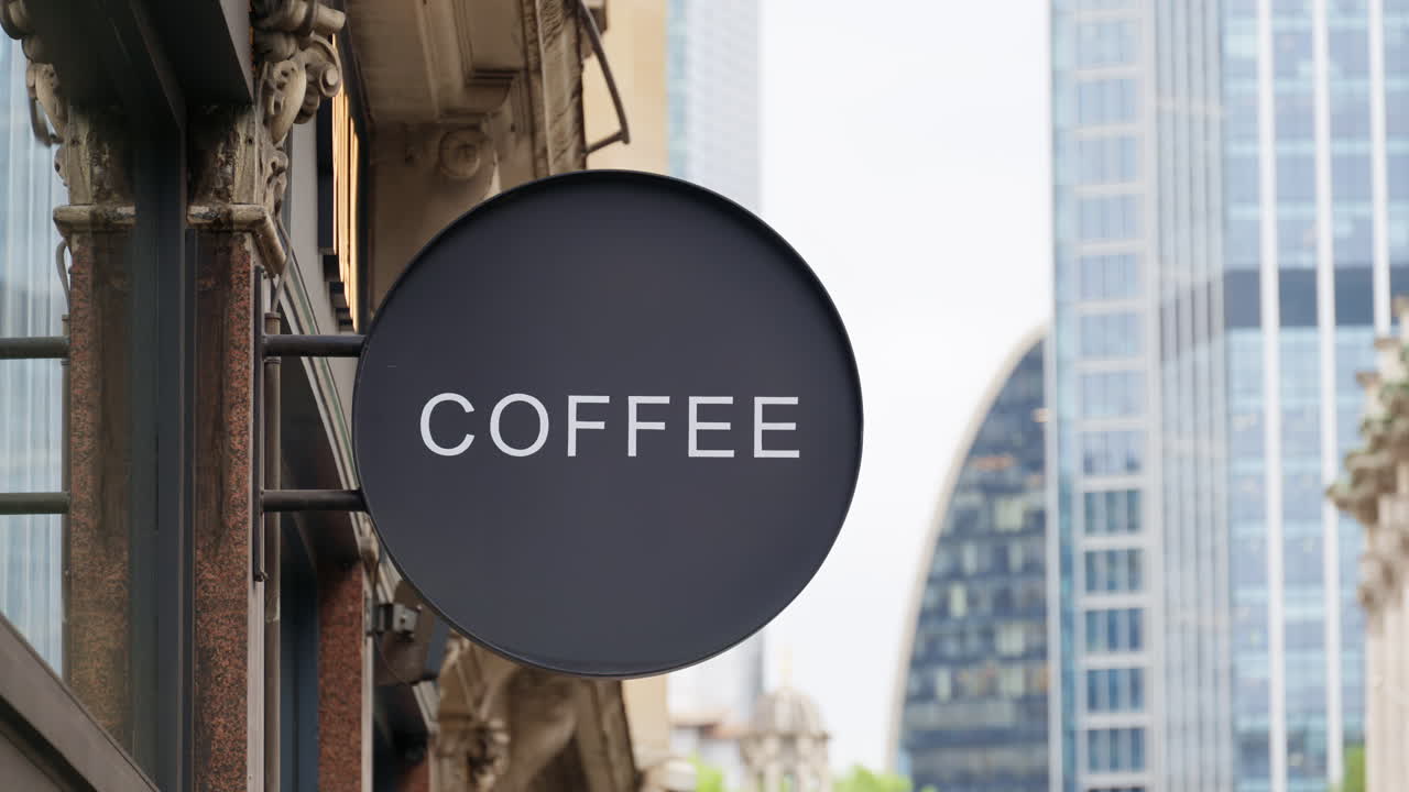 Primo piano di un'elegante insegna circolare nera con la scritta Coffee in bianco, sullo sfondo di un moderno ufficio con vetrate a Londra, Inghilterra