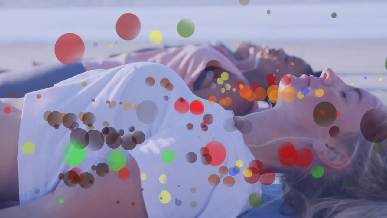 On beach, women relaxing with colorful bubbles floating around them