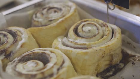 Freshly-Baked-Cinnamon-Rolls-With-Cream-Sauce-On-Baking-Paper---high-angle,-close-up