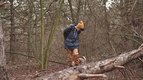 una mujer joven con el pelo corto da un paseo con su perro por el bosque