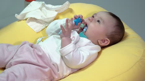 curious baby lying on her back holding a toy during daytime