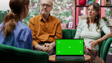 caregiver nurse consulting senior couple next to chroma key mockup display