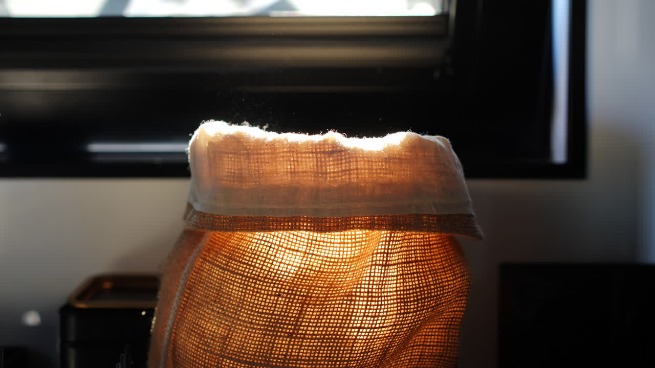 Hand taking bread from fabric sack with flour dust in warm morning backlight