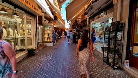 a woman walks through a narrow street market filled with jewelry shops