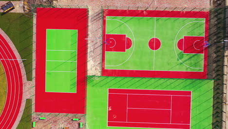sports complex outdoors. green and red artificial grass on fields for doing sport. modern stadiums in the city. top aerial view.