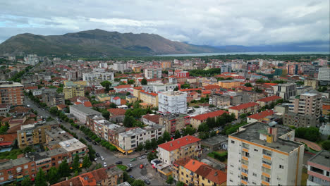 aerial drone forward moving shot over city buildings on both sides of a road in shkoder or scutari in northwestern albania on a cloudy day