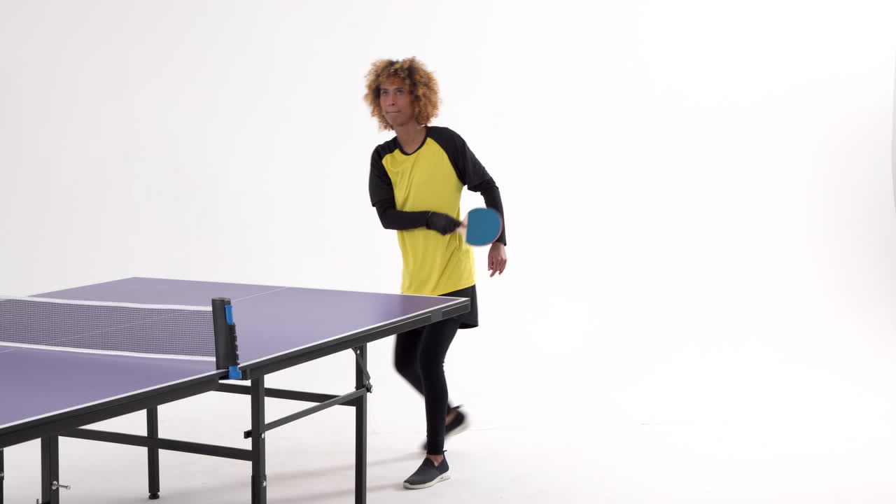 Pemain tenis meja wanita melakukan servis dan mengoper bola dengan latar belakang putih, tersedia ruang kosong.
