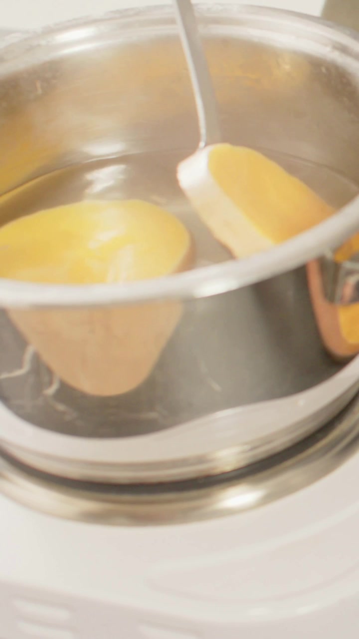 Verticale video: Man schept met metalen lepel gele schijf in hete pan op aanrecht om te koken