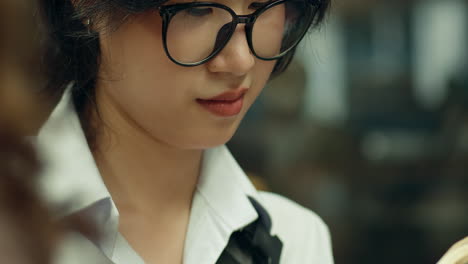 detailed closeup of girl in glasses holding small book and smiling