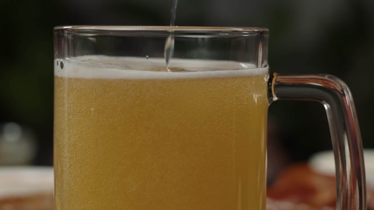 Primo piano di birra dorata versata in un boccale di vetro