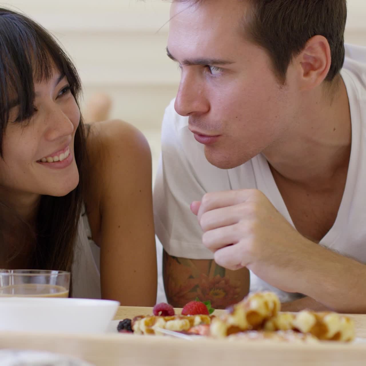pareja desayunando frutas y gofres en la cama