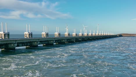 Luftaufnahme-Des-Wassers,-Das-An-Einem-Schönen-Sonnigen-Tag-Durch-Die-Offenen-Schleusen-Des-Oosterschelde-Sturmflutwehrs-In-Zeeland,-Niederlande,-Fließt