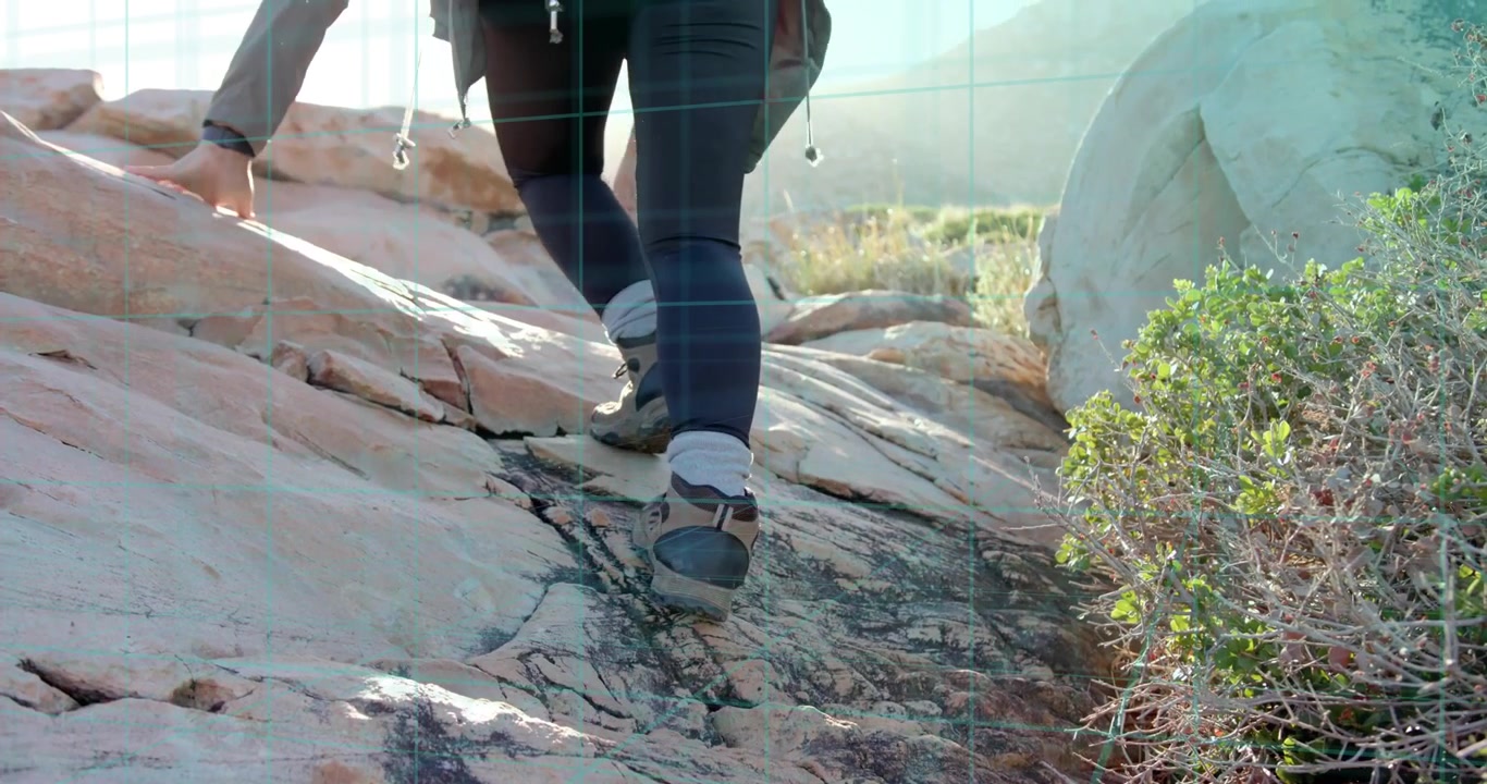 Outdoor hiker initiating ascent by planting foot on ledge steadying with hand climbing desert ridge