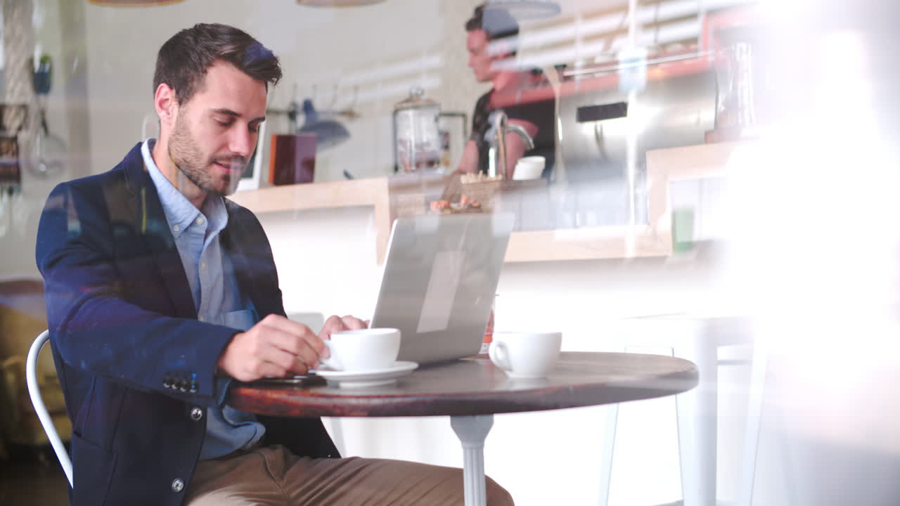 joven empresario en una mesa en un café usando una computadora portátil