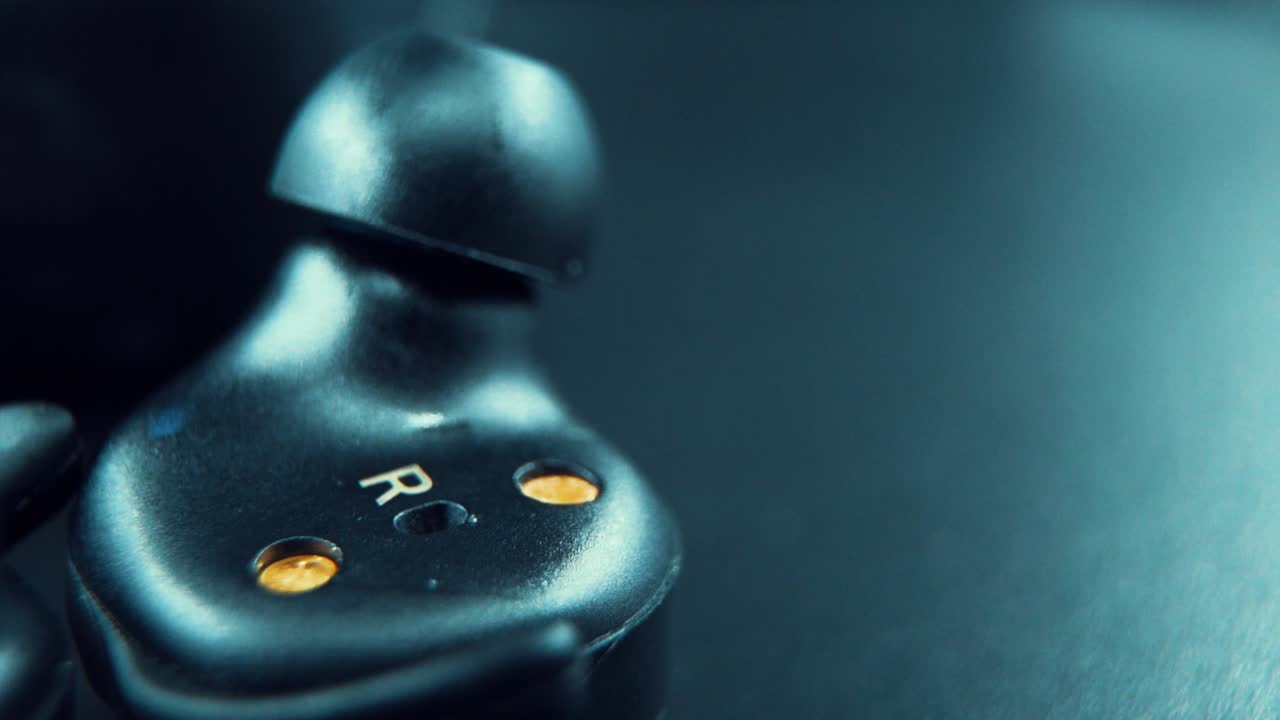 una toma macro cinematográfica de un auricular negro inalámbrico auricular al revés, iluminación de estudio, 120 fps, cámara lenta, full hd