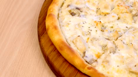 la mitad de la pizza en rebanadas con setas champignons y queso en tabla de madera en la mesa. vista lateral de primer plano.