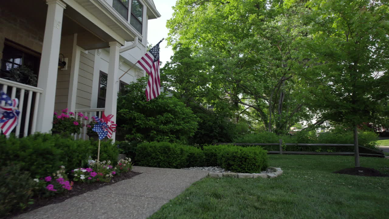 Gående forbi forsiden af et pænt hus dekoreret med patriotisk pynt og et amerikansk flag