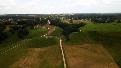 a drone footage of lush green fields and trees in kernave mounds in lithuania