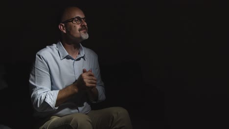 depressed mature man struggling with mental health sitting in darkness on sofa with low key lighting 8