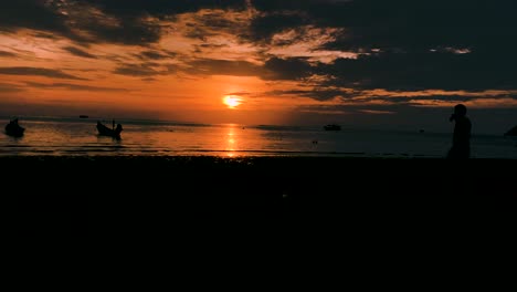 Gente-Y-Barcos-En-La-Impresionante-Playa-De-Sairee-En-Koh-Tao,-Tailandia---Timelapse-Del-Movimiento-De-La-Puesta-Del-Sol-A-La-Noche