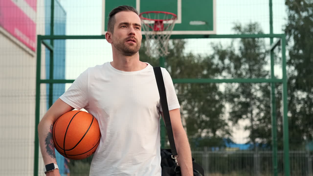 hombre sosteniendo una pelota de baloncesto en la cancha al aire libre