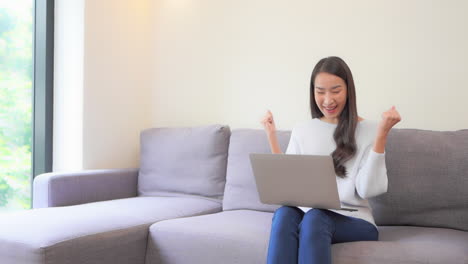 a young pretty woman working on her laptop celebrates a task well done