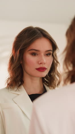 elegant lady with bright makeup enjoys looking in mirror in beauty studio. young woman with ginger hair smiles examining own reflection closeup