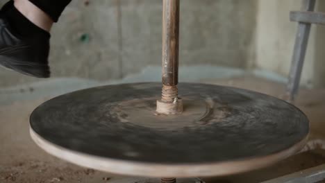 Spinning-pottery-wheel-close-up.-Foot-of-potter-working-in-pottery-workshop.-Beautiful-young-woman-working-on-vase-in-pottery-master-class.-Close-up.-Slow-motion