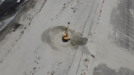 aerial drone birdseye footage of an excavator digging on sandy beach in cohasset, ma usa