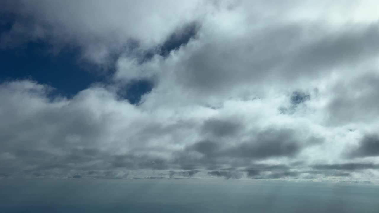 A plilot&rsquo;s perspective from a jet cabin while flying just under a layer of thin stratus clouds