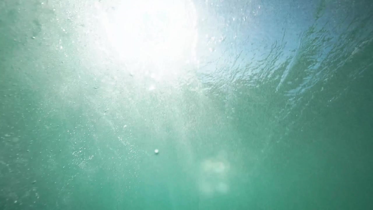 スローモーションで差す太陽光の水中からの眺め