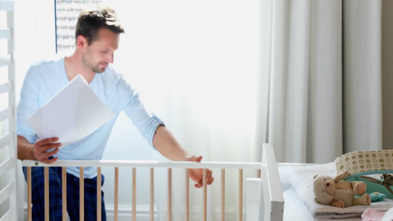 Uomo che prepara la culla con donna incinta in camera da letto 4k