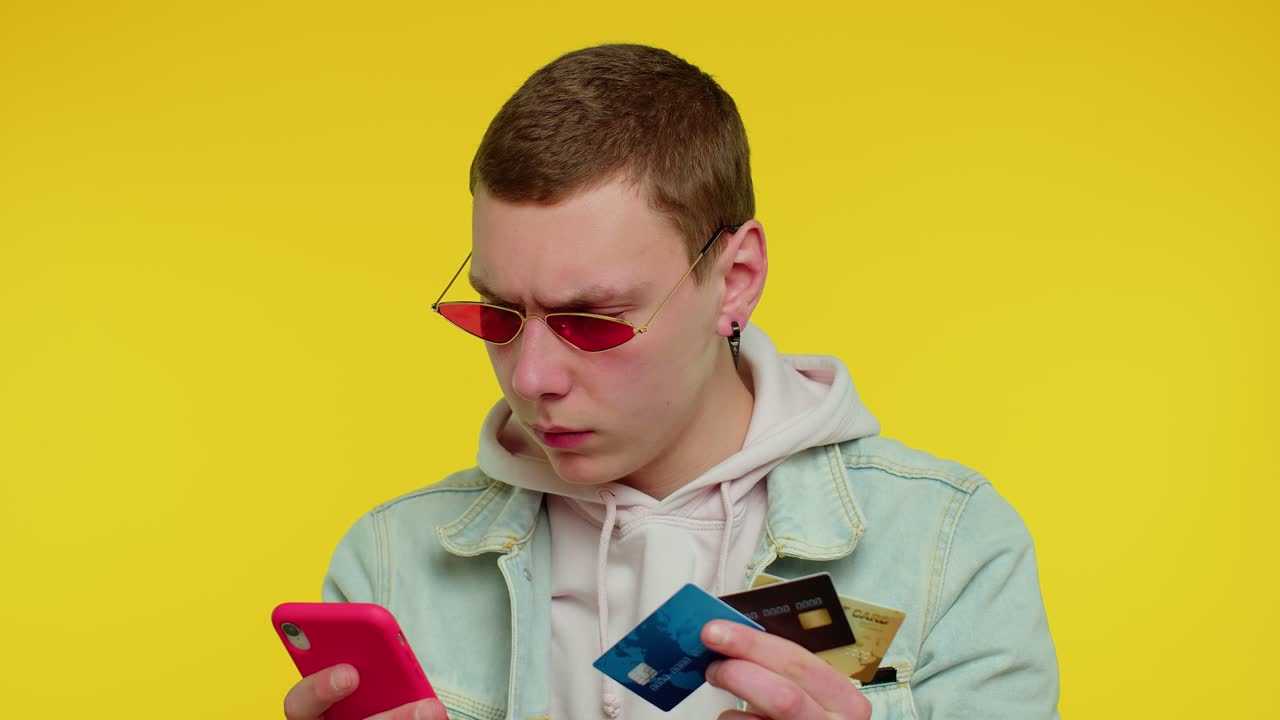 hombre adolescente usando tarjetas de crédito bancarias y teléfonos inteligentes mientras transfiere dinero, compra compras en línea