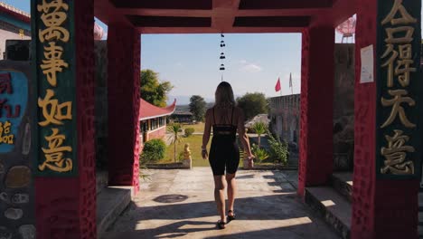 Blonde-woman-in-black-sportswear-walks-through-the-gate-of-the-historic-Chinese-village-of-Santichon-in-Thailand-on-a-warm-summer-afternoon