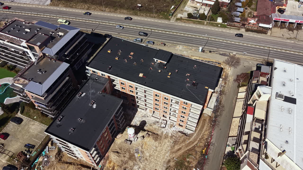 Cantiere che mostra nuovi edifici vicino a una strada principale in una zona trafficata durante una giornata di sole in città