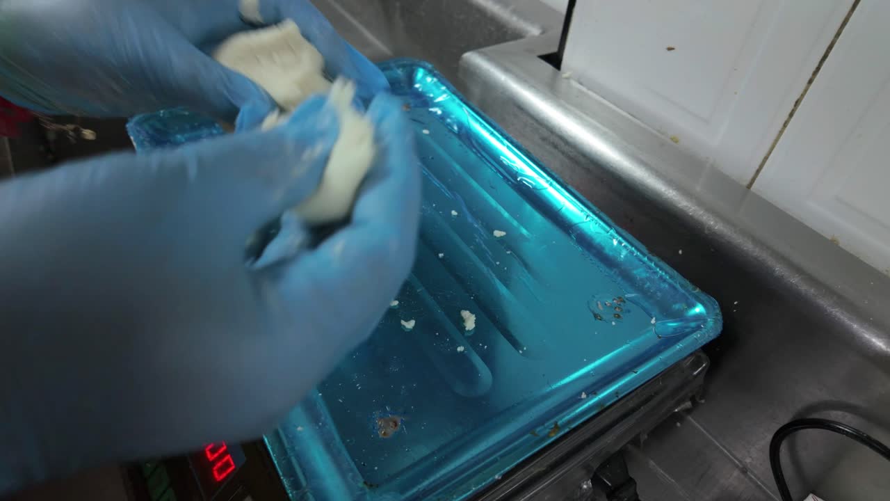 woman's hands using a digital scale to ensure precision in a traditional food-making process