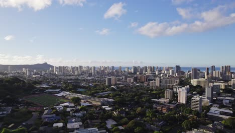 pan right drone shot of the city of honolulu hawaii on a sunny afternoon with blue sky featuring tall buildings in the urban setting against the pacific ocean