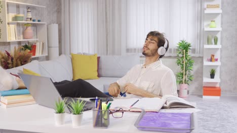 Young-Man-Using-Laptop-At-Home-Listening-To-Music-With-Headphones.