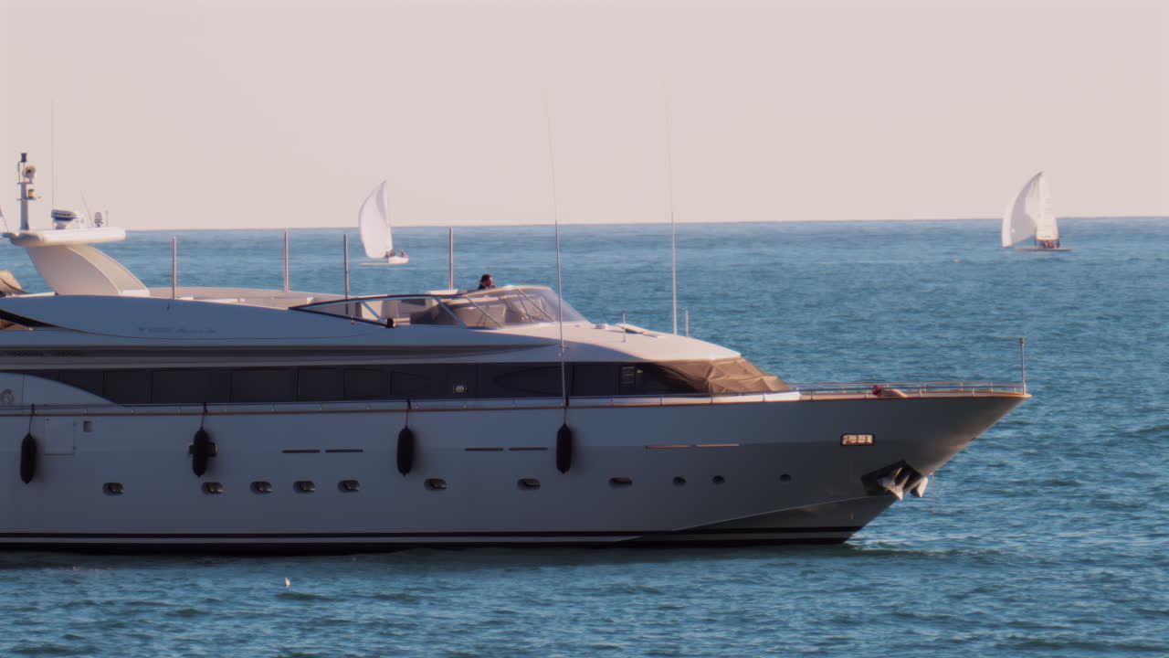 Nice, France - February 10, 2025: A boat with the flag of Monaco moving on the sea with small sailboats on the background