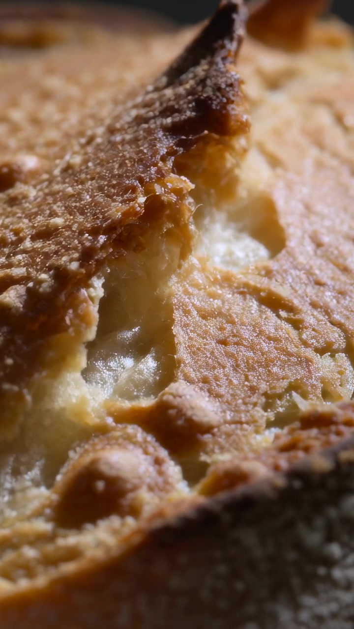 Video verticale: Inquadratura che si sposta rivelando una fetta di pane tostato che si strappa per esporre l'interno filante su un vassoio.